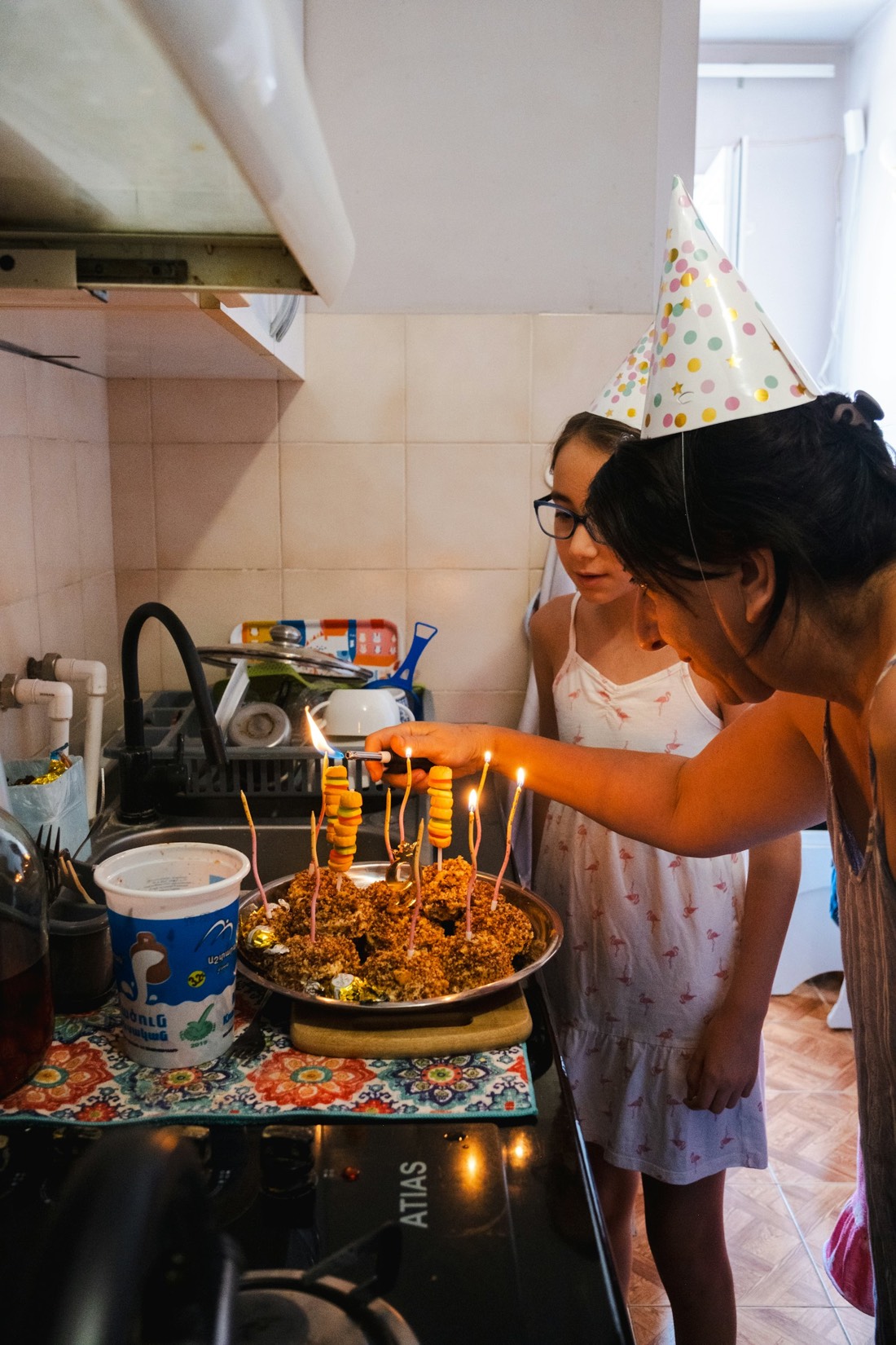 Dos personas con gorritos de fiesta encendiendo las velas de una tarta