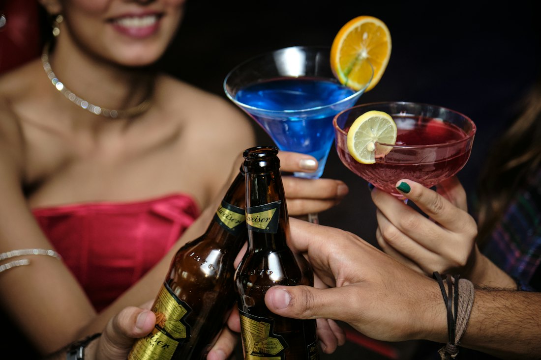 Friends clinking cocktail glasses and bottles