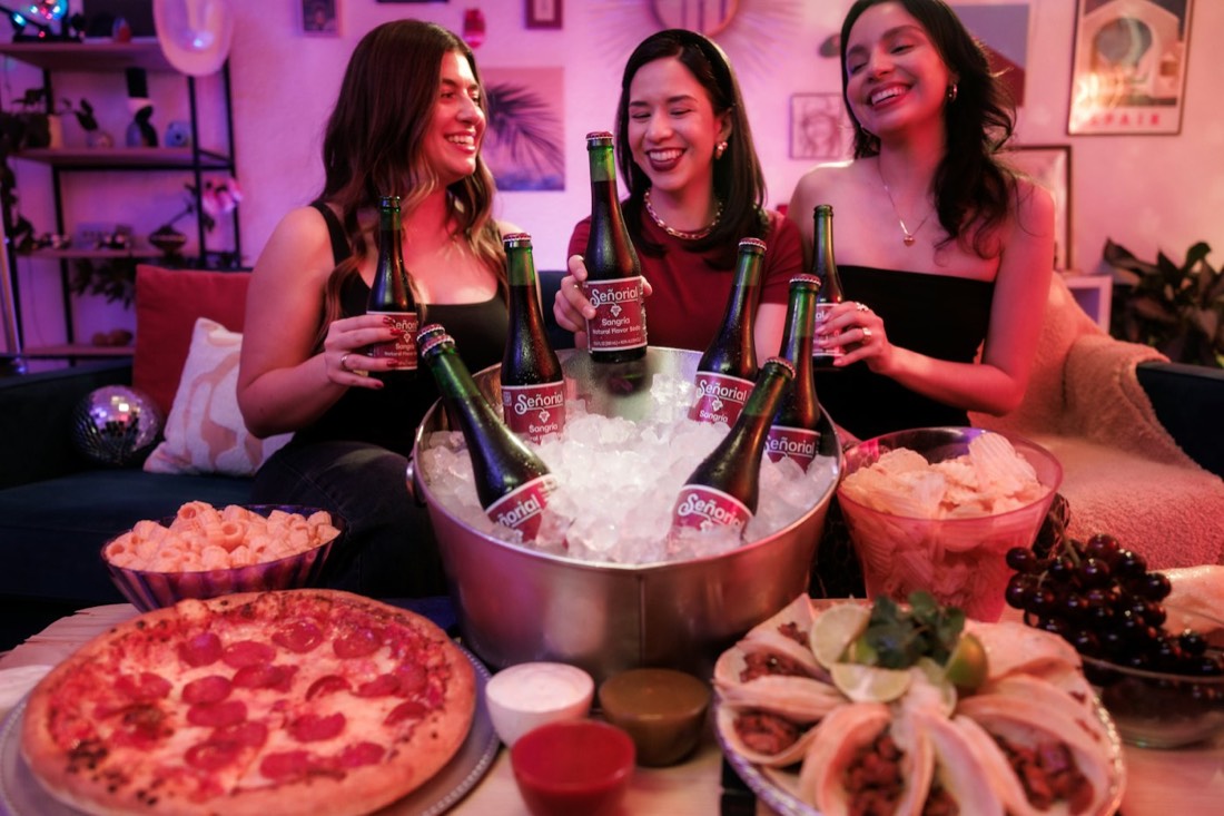 Three friends having drinks and snacks at a house party