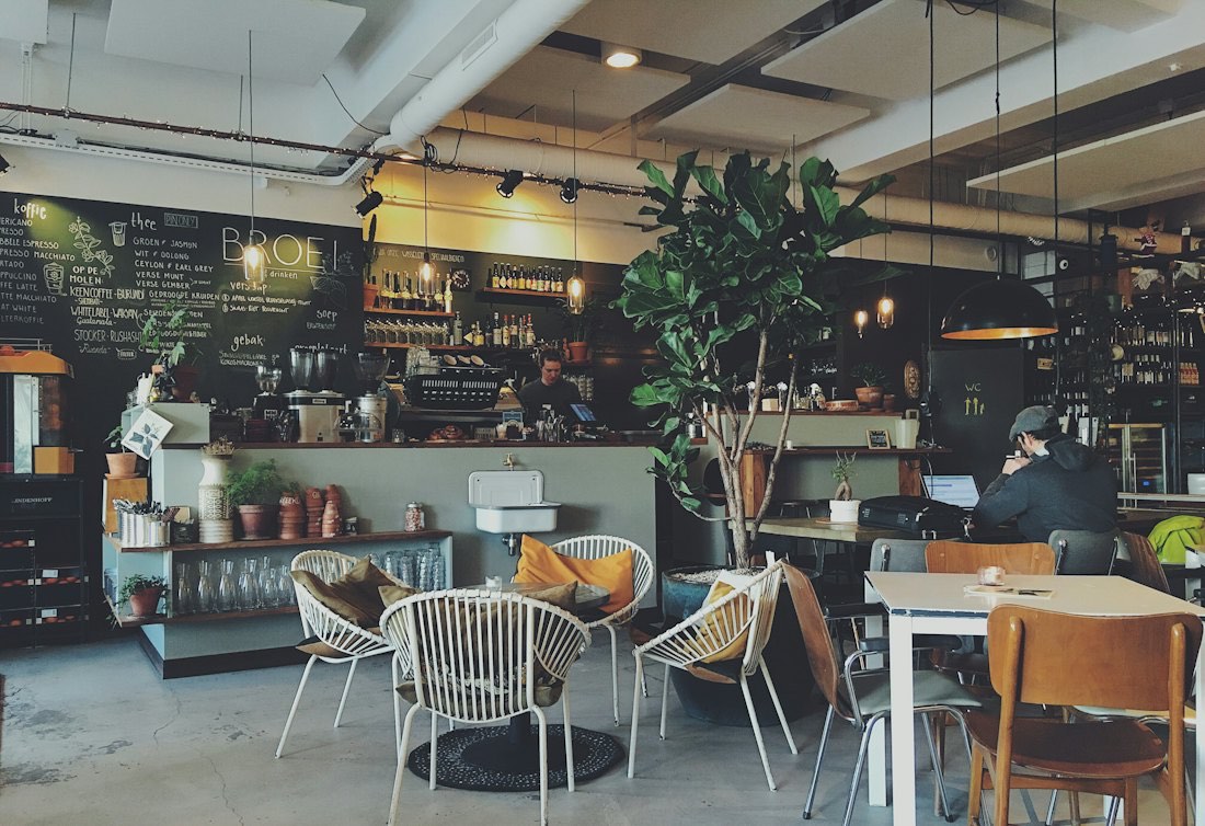 A small café with a counter, plants and hanging lights