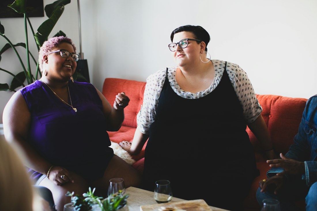 Two friends laughing and chatting on a sofa at home